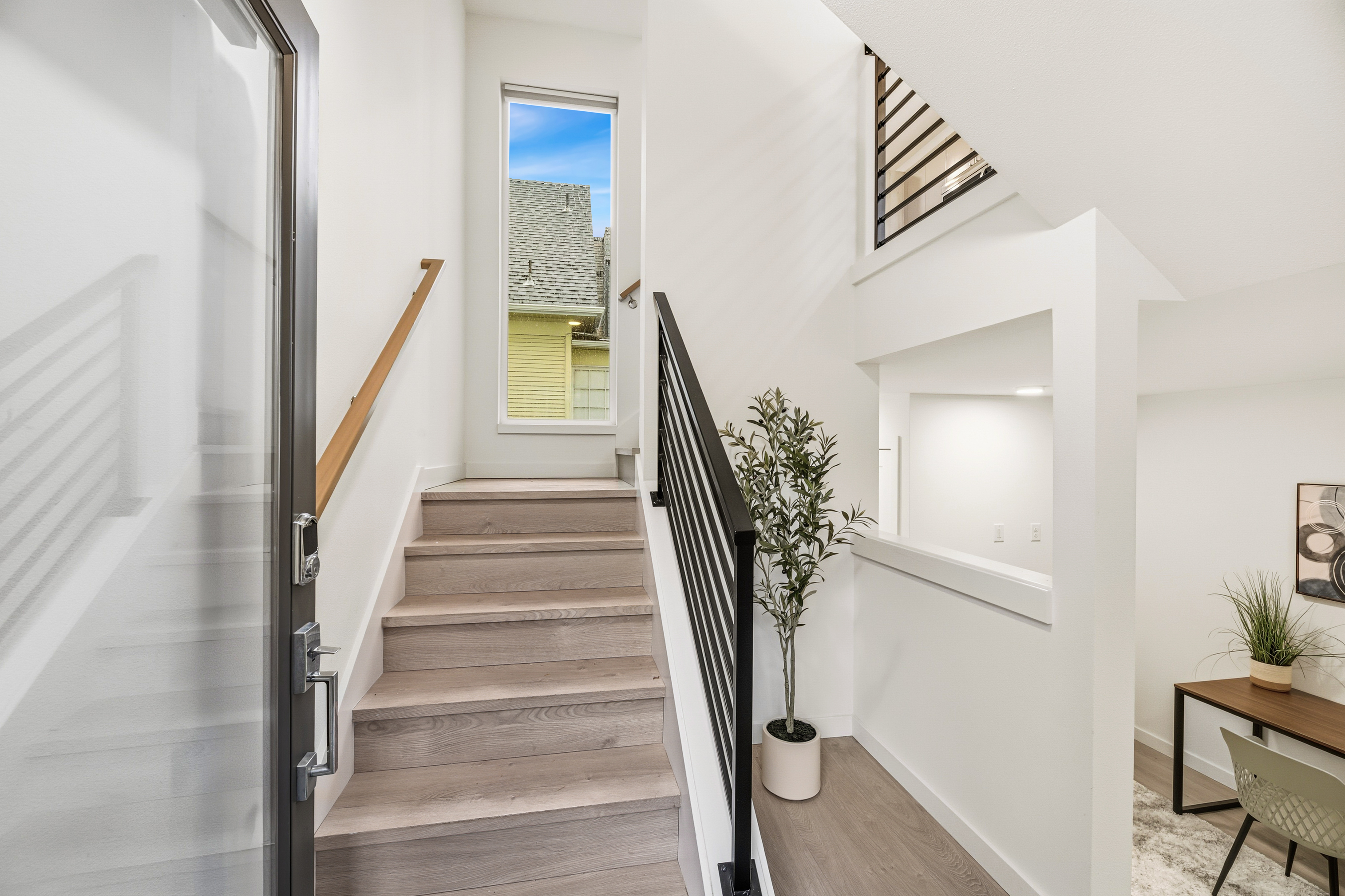 Bright interior staircase with light wood flooring and modern black railings