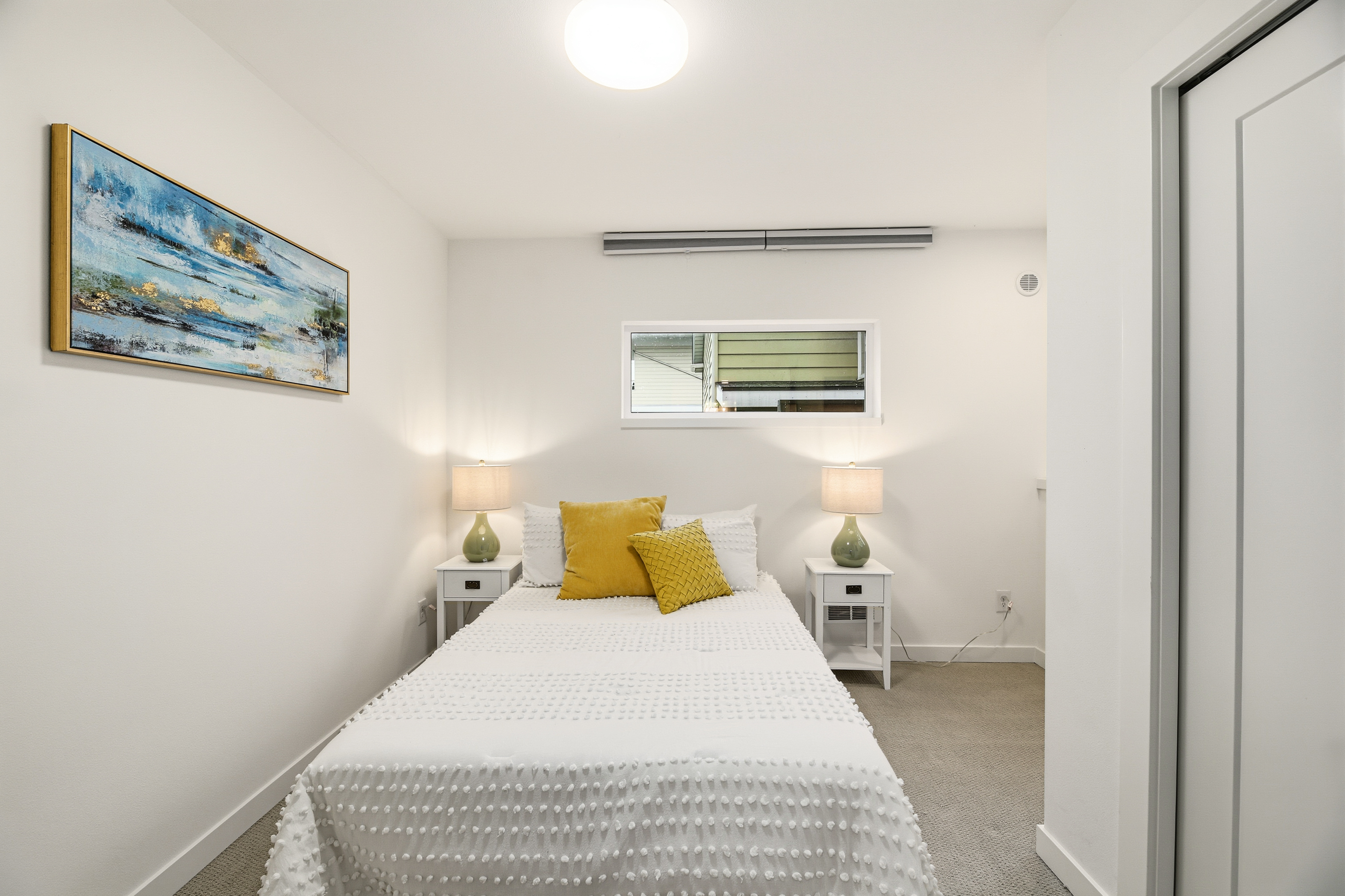 Bedroom with yellow accent pillows and modern art